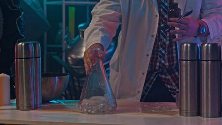A man in a medical coat is mixing chemicals in a glass flaskの写真素材