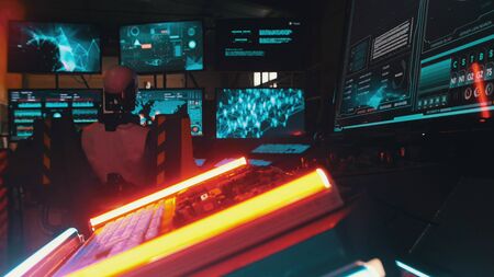 Robot is sitting at the computer in the room with a lot of lasers and screens
