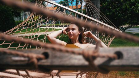 Pretty young woman is looking on the left in hammock and smilingの写真素材