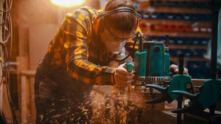 Carpentry indoors - a man woodworker polishes the top of the plankの写真素材