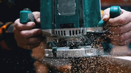 Carpentry indoors - a woodworker polishes the wooden detail - sawdust falling down from the detail...