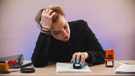 office - a tired woman putting a stamp on the document
