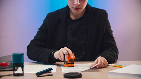 office concept - a woman putting a stamp on the document with a orange seal