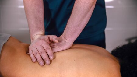 Chiropractic treatment - the doctor giving the patient a massage - softly pushing down on the lower back with handsの写真素材