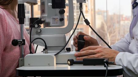 Ophthalmology treatment - a doctor checking young woman's visual acuity with a special machine in a...