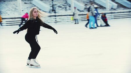 A young woman figure skater skating on the ice rink around peopleの写真素材