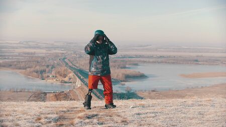 Snowboarding - A man with prosthetic leg standing on the board and putting on protective glasses and helmet. Mid shotの写真素材