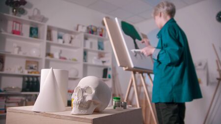 A young woman artist drawing a painting - different figures on the foregroundの写真素材