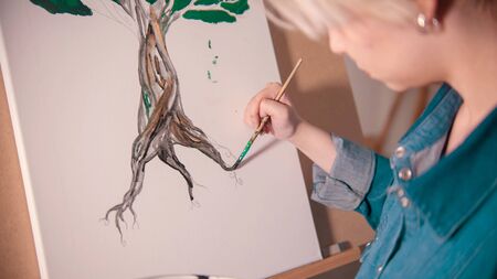 A young woman painting tree trunk in darker colorの写真素材