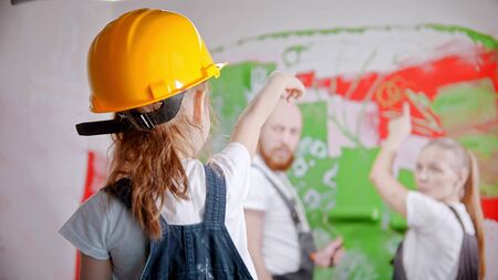 A little girl in a helmet pointing at the wall - her parents standing next to the wall