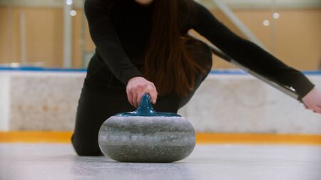 Curling - holding a granite stone with blue handle on the ice field. Mid shotの写真素材