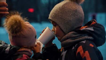 A little girl and boy drinking hot drinks outdoors. Mid shotの写真素材