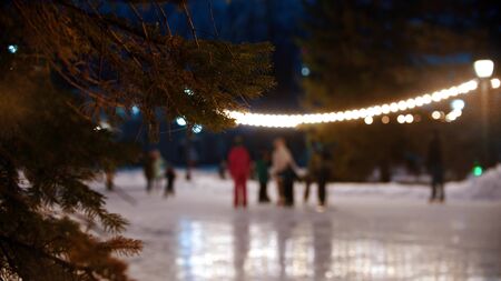 People skating on the public ice rink while christmas outdoors. Mid shot