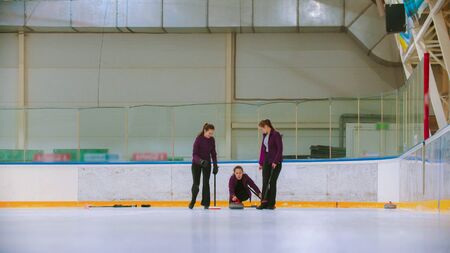 Curling training indoors - team group of three women leading the granite stone. Mid shot