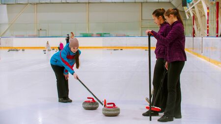 Curling training - the judge measuring the distance between two stones on the ice rink