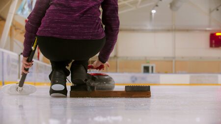 Curling training - a woman standing near the pushing off stand. Mid shotの写真素材