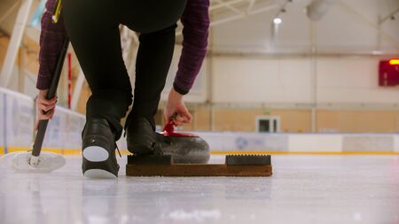 Curling training - a woman about to push off the stand on the ice field. Mid shotの写真素材
