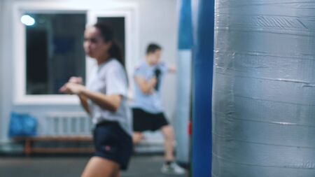 Men and women training in the gym - a woman performing a shadow-boxing. Mid shotの写真素材