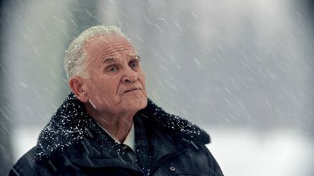 An old gray-haired man under the snowfallの写真素材