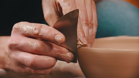 Pottery - a man with an spatula is helping himself maintaining the shape of a bowlの写真素材