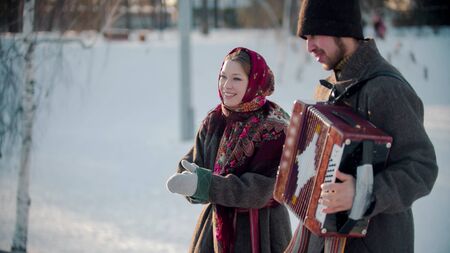 Russian folklore - russian man playing accordion outdoors and smiling woman standing next by himの写真素材