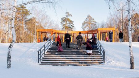 Russian folklore - young people in felt boots are dancing on the stairs in the modern winter park - outdoorの写真素材