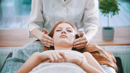 Massage - masseuse kneading the neck area to a young woman using her palmsの写真素材