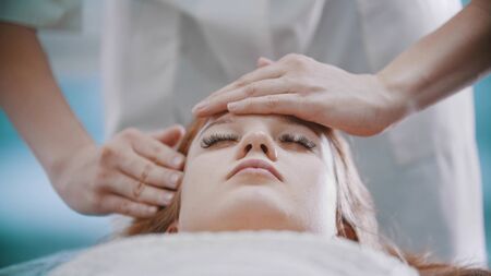 Massage - female masseuse is kneading her clients face with palmsの写真素材