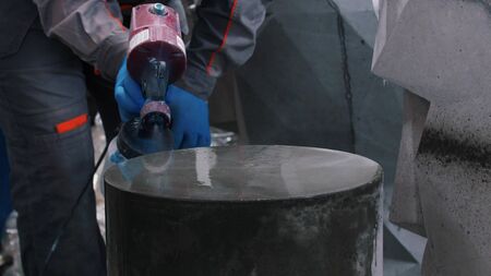 Concrete workshop - worker spraying mortar on a concrete product - indoor