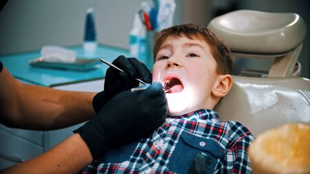 A little boy having a treatment in the modern dentistry - searching for the caries using instrumentsの写真素材