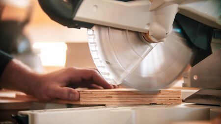Carpentry industry - man cutting out the piece of wood using big circular sawの写真素材