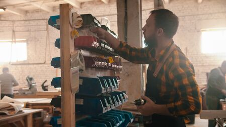 Carpentry industry - bearded man worker choosing screws on the standの写真素材