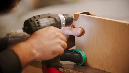 Carpentry - worker drills holes into the plywood. Mid shotの写真素材