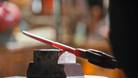 Making a knife out of hot metal using a pressure machine. Mid shot