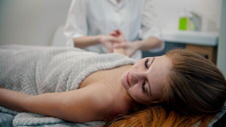 Massage - female young massage therapist massaging hands of her woman clientの写真素材