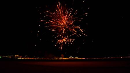 Red fireworks explode late at night on the streetの写真素材