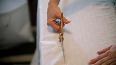 Young woman designer cutting a white cloth. Mid shot