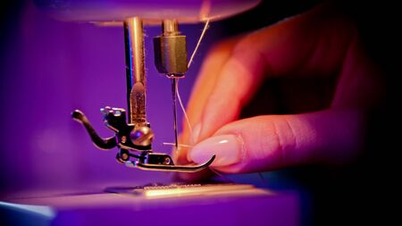 Hand of woman seamstress puts a thread in the eye of a needle. Mid shotの写真素材