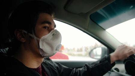 Young man in protective mask driving a carの写真素材