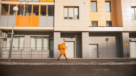 Man courier in yellow clothes delivers food - walking near the porch