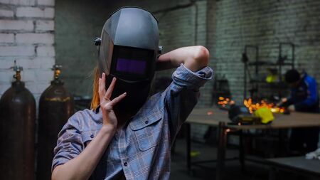 Young sexy woman standing in the workshop in protective helmetの写真素材