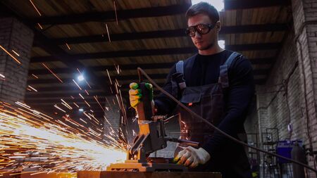 Young handsome man using a grinder to cut the detail