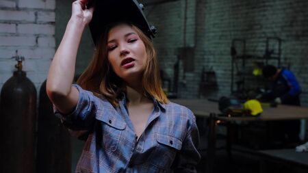 Young sexy woman standing in the workshop and putting on a helmetの写真素材