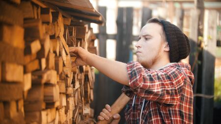 Young man woodcutter with ax puts out the log from the standの写真素材