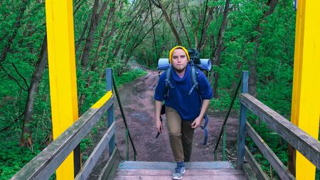 Young man traveler walks on the bridge in the forestの写真素材