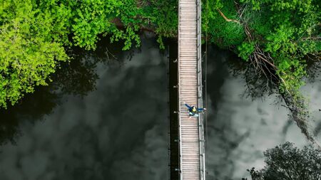 Young happy man traveler with big backpack walking on the bridge in the forest. Mid shotの写真素材