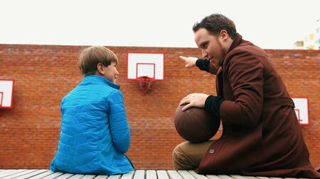 Young man and his little brother on the basketball playgroundの写真素材