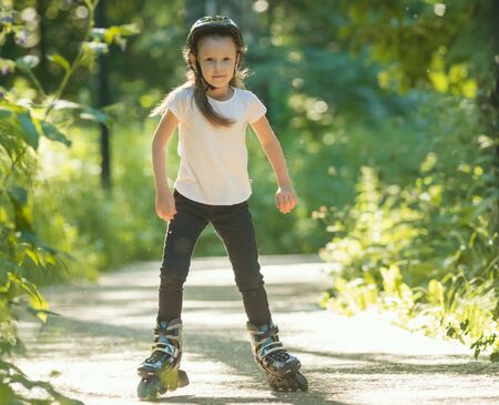 A little girl in protective helmet skating in the park on her rollersの写真素材