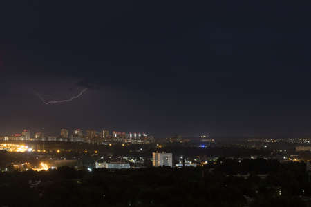 Lightning flashes in the night cloudy sky above the city