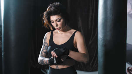 Tattooed woman binding her hands before box training
